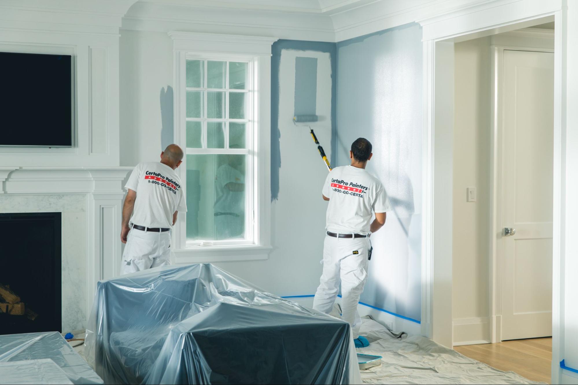 two painters in white uniforms painting the interior of a home