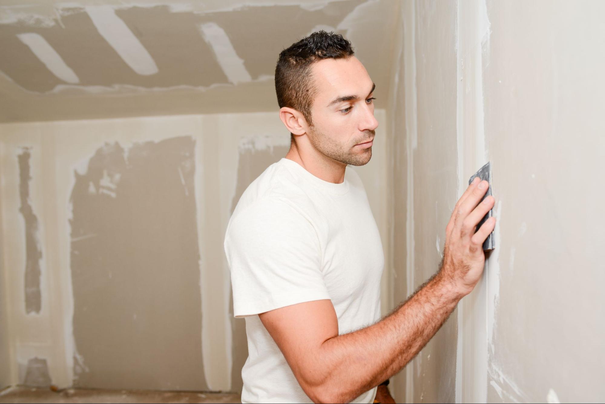 a man using a sander to sand down drywall
