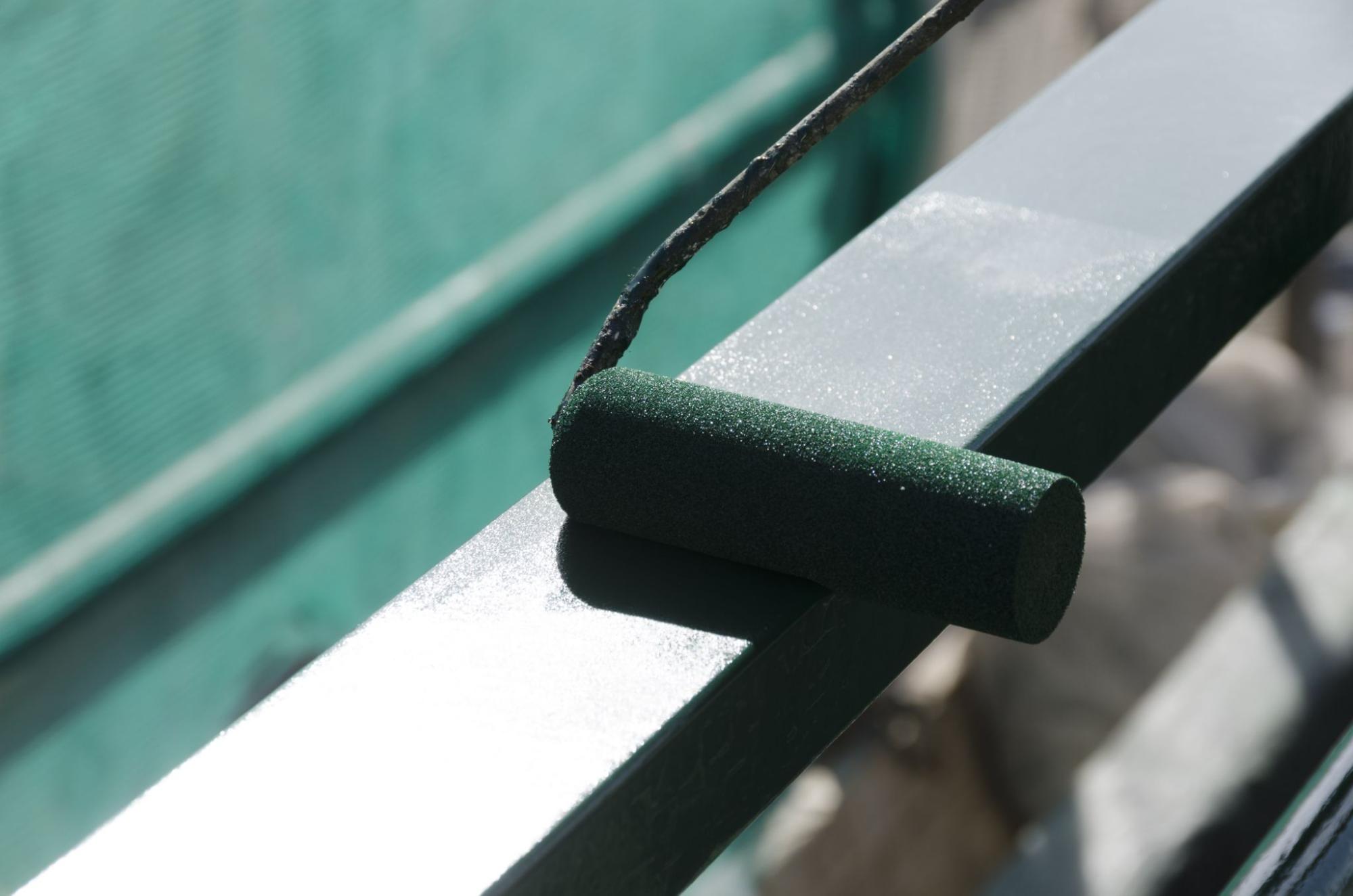 a shot of a paint roller painting on a metal railing 