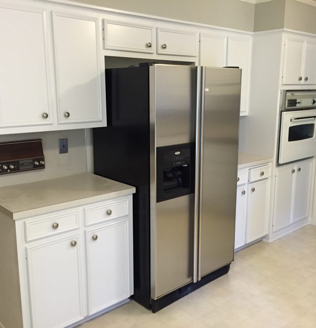 interior of kitchen showing fridge with painted cabinets